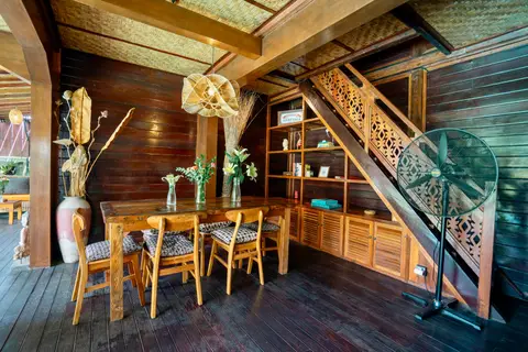 Rumah Elfi: dining table under the carved wooden staircase