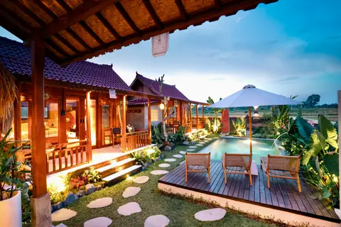 Joglo Hati: pool and houses lit up in the evening