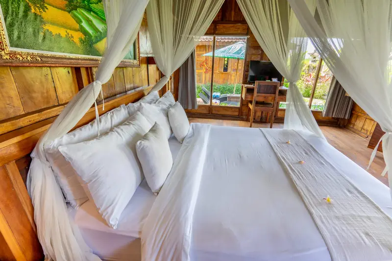 Rumah Richard: bed with white cushions and a mosquito net